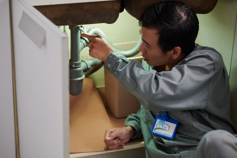 Plumber fixing a leak under the sink